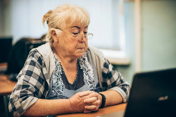 Elderly woman sitting in front of a laptop. Training of pensioners using modern remote technologies.