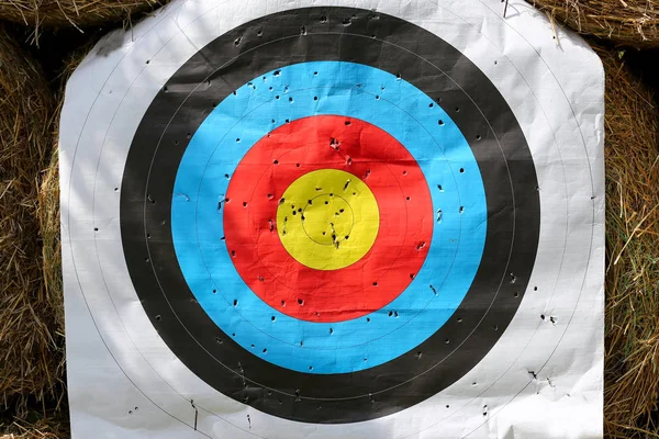 Colorful target template for sport shooting competition. Used target with color circles on shooting range against hay bales