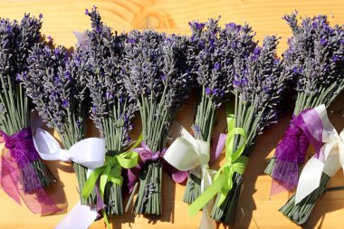 Menekşe kurdeleli bir demet lavanta. Eski ahşap masa üzerinde taze lavanta çiçeği buketi. Mor bitkisel çiçek. Lavanta aromaterapisi 