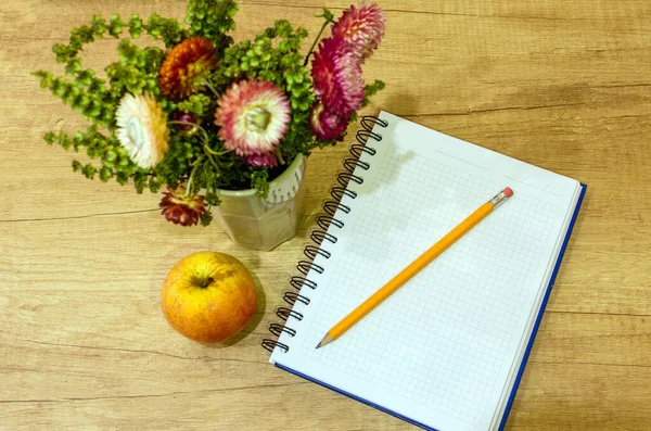 オフィスの机の上からの眺め 木のテーブルの上のノートや花や鉛筆やりんご — ストック写真