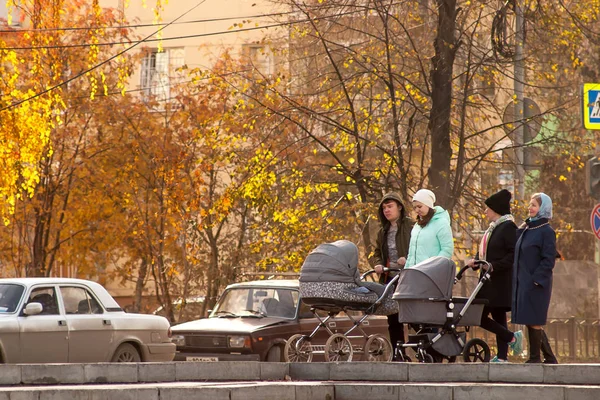 Yekaterinburg, Russia.October 15 2017-genç çift bir bebek arabası ile sonbahar şehir etrafında yürüyor. İki genç kadın arabaları ile aileleri ile birlikte yürüyor. Hafta sonu boyunca aile yürüyüş