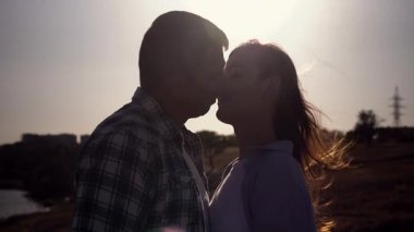 Gün batımında öpüşen genç bir çiftin silueti. Romantik yavaş çekim sahnesi, doğadaki aşkı, samimiyeti ve duygusal bağı sıcak altın ışıkla yakalıyor.. 