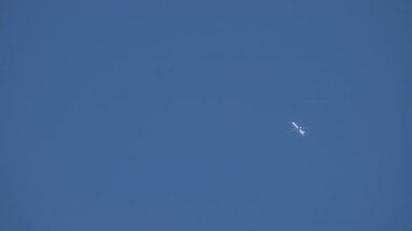 Mavi gökyüzünde yükseklerde uçan uçak. Yavaş çekim. 