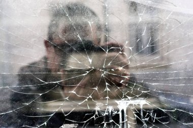 Adam kırık pencerede yansıma ile akıllı telefon kullanarak selfie yapma