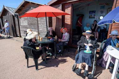 Clacton Beach Hut tarafından oturan rahatlatıcı insanlar