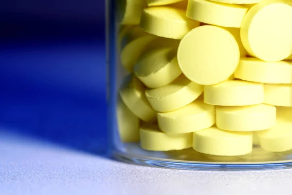 Желтые таблетки в стеклянной бутылке — стоковое фото