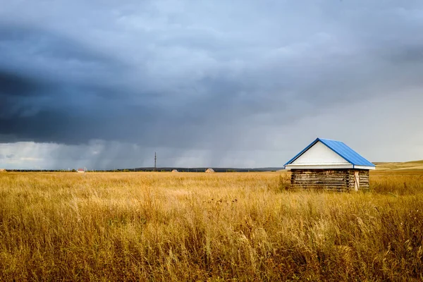Holzhütte in einem Feld mit Regenwolken — Stockfoto