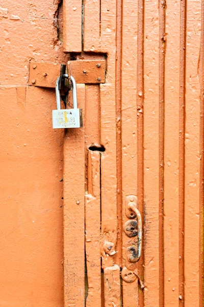 Запертая оранжевая окрашенная сельская дверь — стоковое фото