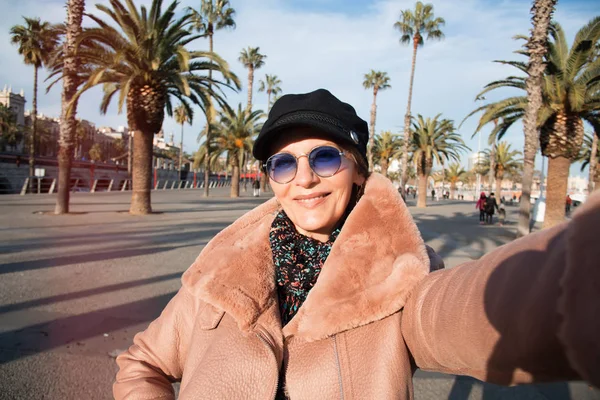 Fashion Model In Street. Woman In Stylish Fashionable Fall Clothes. Mature woman In High Fashion Autumn Clothing Posing Outdoors.smiling mature woman  making selfie on the background of the city