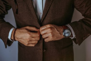 Onun kol düğmeleri tamir takım elbiseli adam. Moda portre rahat bez genç işadamı yakışıklı modeli adamın uygun.