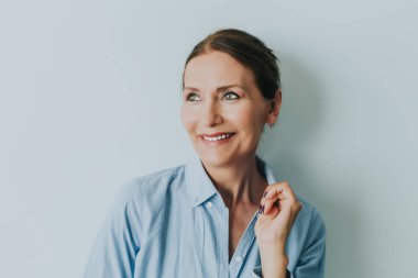 Gülümseyen güzel olgun kadın. Gülümseyen ve duvar dibinde duran güzel olgun kadın portresi kapatın. İş kadını gülümseyen bardakları ile portresi.