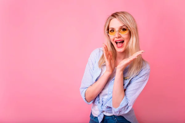 Blonde fashionable woman with surprised face on pink background. Surprised face. Successful emotions. Wearing trendy striped shirt.Copy space.Horizontal.