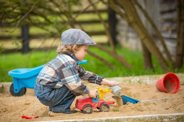 砂の穴で遊んでいる小さな白人の少年 ハンサムなブロンド4歳男の子で彼のサンドボックス ストック写真