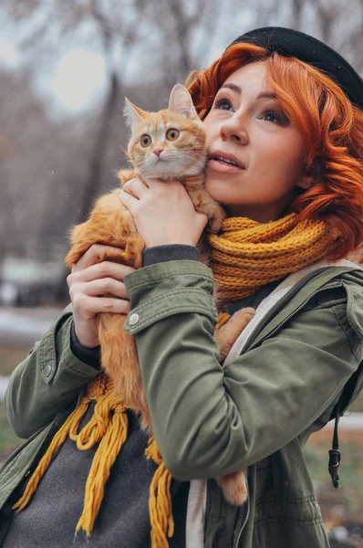 Retrato de uma menina ruiva com um gato vermelho na rua Imagens De Bancos De Imagens