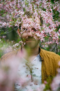 Yeşil ve gür pembe badem çiçekleri Genç sevimli şık adam rüyalar