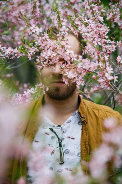 Yeşil ve gür pembe badem çiçekleri Genç sevimli şık adam rüyalar