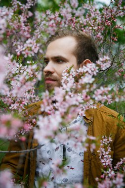 Yeşil ve gür pembe badem çiçekleri Genç sevimli şık adam rüyalar