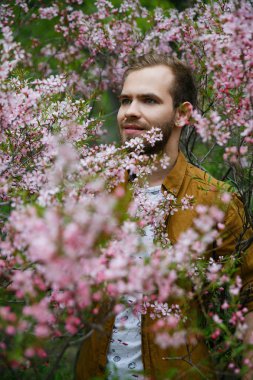Yeşil ve gür pembe badem çiçekleri Genç sevimli şık adam rüyalar