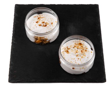 Beyaz bir arka plan üzerinde siyah bir taş tabak üzerinde bir kavanozda Bal cheesecake tatlı