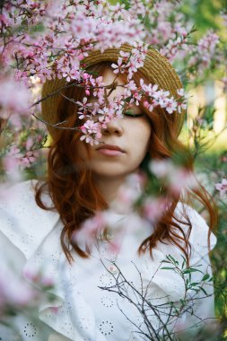 Güzel kızıl saçlı kız poz ve bahar badem çiçekleri rüya