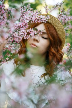Güzel kızıl saçlı kız poz ve bahar badem çiçekleri rüya