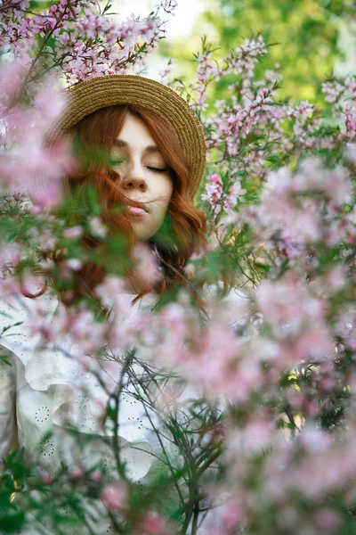 Güzel kızıl saçlı kız poz ve bahar badem çiçekleri rüya