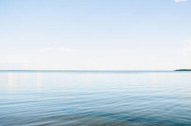 Sakin su ve berrak gökyüzü ile bir yaz akşamında gün batımında