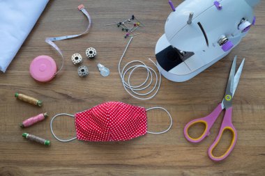 Ahşap arka planda kumaş yüz maskesi yapmak için kullanılan aksesuar ve makinelerin üst görüntüsü. Zanaat.