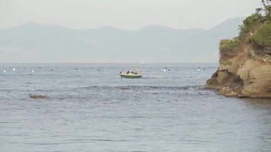 küçük bir tekne bir ada Dağları ile arka plan üzerinde deniz boyunca yelken