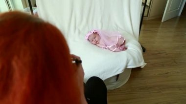 Fotoğrafçı yeni doğmuş bir kızı fotoğraf çekimi için hazırlıyor, üstünü değiştiriyor, poz değiştiriyor.
