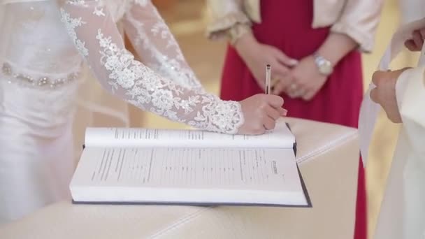 De ceremonie van het huwelijk in de kerk, de bruid en bruidegom teken — Stockvideo