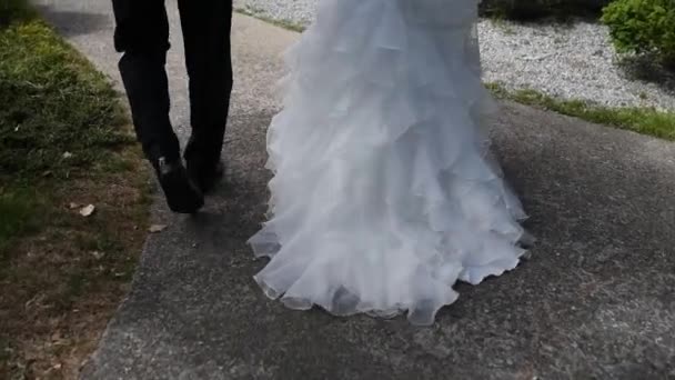 Utsikt över benen, bruden och brudgummen promenader, en vacker tåg klänning — Stockvideo
