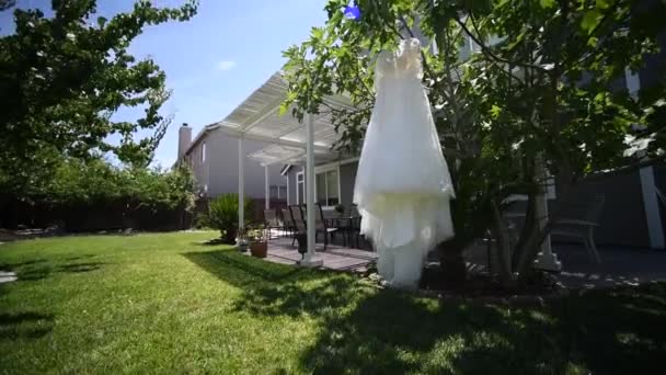 Vestido de noiva de casamento pendurado em uma árvore. guirlandas e pano ao ar livre . — Vídeo de Stock