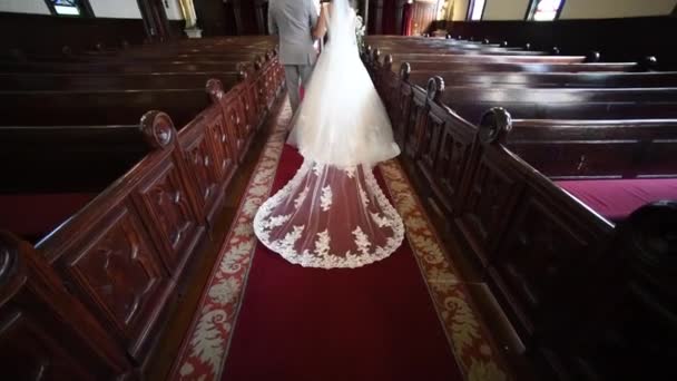 View of the legs, the bride and groom go in church, beautiful train dress — Stock Video