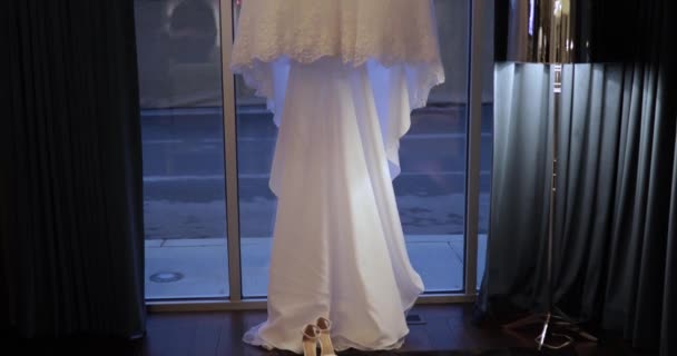 Vestido de novia colgando en la habitación contra la ventana — Vídeos de Stock