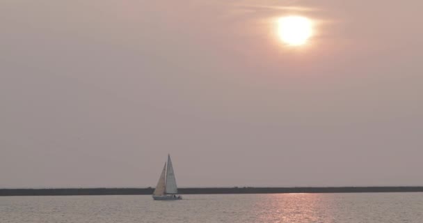 Vista desde lejos, un yate en la niebla contra el sol poniente — Vídeos de Stock