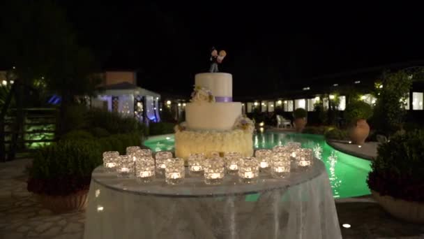 Große Hochzeitstorte vor dem Hintergrund des Pools, Schieberegler, Nacht — Stockvideo