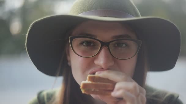 A lány a szemüveg és a széles karimájú kalap, az undor, eszik, szendvicset, közeli.