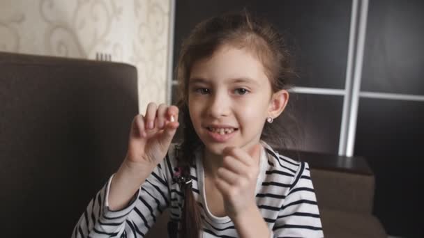 kleines Mädchen freut sich über den gefallenen Zahn. Porträt eines kleinen Mädchens, das vor der Kamera einen gefallenen Babyzahn zeigt.