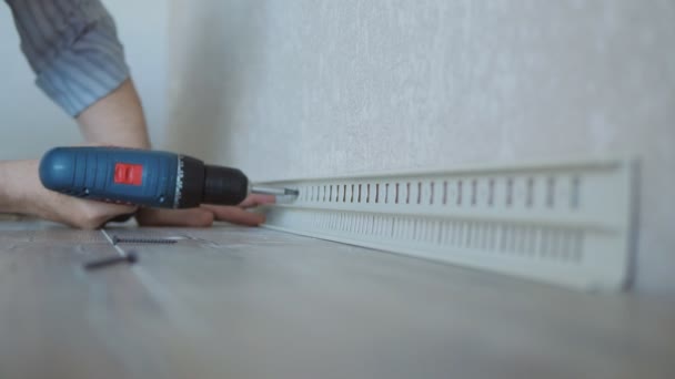Close-up of A man uses a screwdriver to screw a self-tapping screw into a drywall wall fixing the skirting Board. — Stock Footage Close-up of A man uses a screwdriver to screw a self-tapping screw into a drywall wall fixing the skirting Board. Video Clip