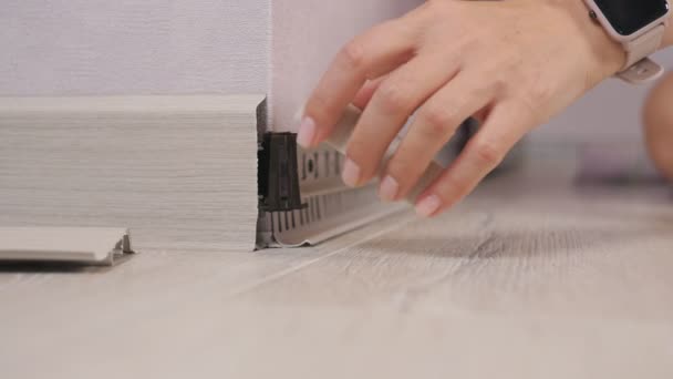 Close-up of womens hands mounting the skirting Board in the room. the woman fixes the skirting Board and puts the outer corner on the fastenings. — Stock Footage Close-up of womens hands mounting the skirting Board in the room. the woman fixes the skirting Board and puts the outer corner on the fastenings. Stock Footage
