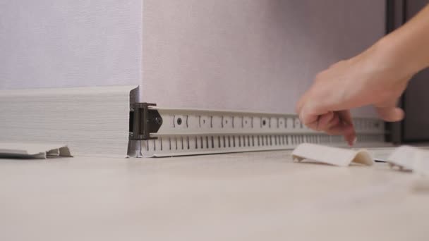 The process of installing a baseboard on the wall in an apartment. Close-up of mens hands setting the baseboard. — Stock Footage The process of installing a baseboard on the wall in an apartment. Close-up of mens hands setting the baseboard. Video Clip