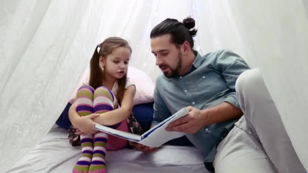 Little girl and her father reading a book together — Stock Video