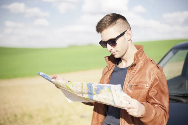 Turistický muž vedle vozu se dívá na mapu oblasti. Cestovatel — Stock fotografie