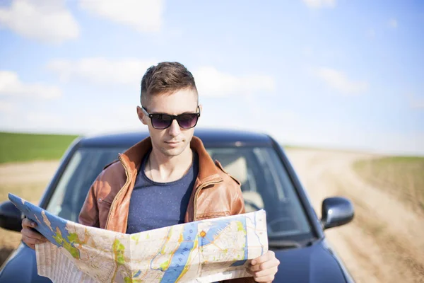 Un turista vicino alla macchina guarda la mappa della zona. Viaggiatore — Foto Stock