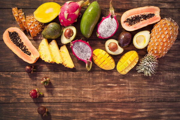 Tropical fruits, papaya, Dragon Fruit, rambutan, tamarind, avocado, granadilla, carambola kumquat mango passionfruit On a wooden background. Ассорти
