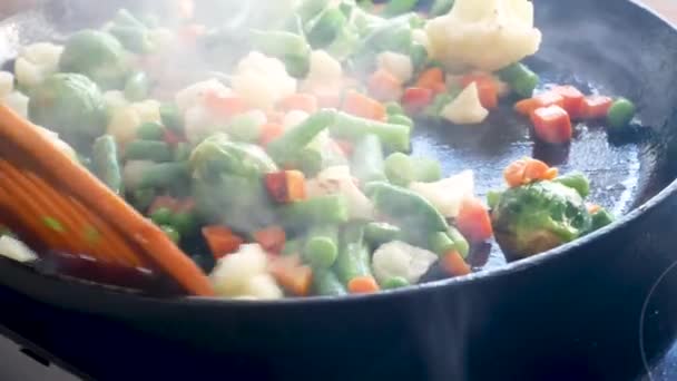 Costeletas e legumes são fritos em óleo de girassol na frigideira. Close-up. Feijão, cenouras, couve-flor — Vídeo de Stock