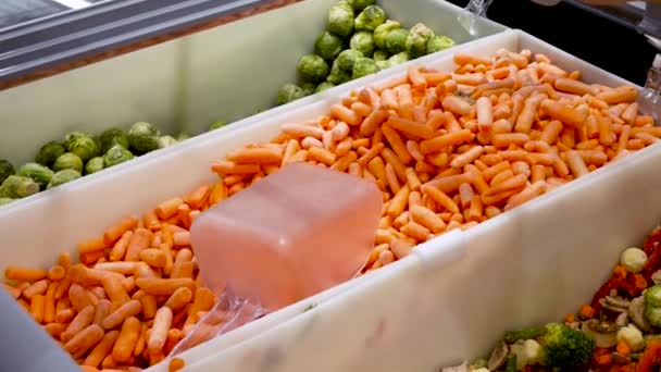 Man buys carrot in the mall. a young guy picks up frozen carrot Selection of Frozen Close- up — Stock Video