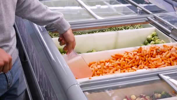 L'homme achète des carottes dans le centre commercial. un jeune homme ramasse des carottes congelées Sélection de Frozen Close- up — Video