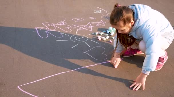 Ребенок рисует в парке. Девушка рисует мелом на асфальте . — стоковое видео